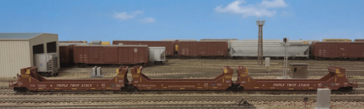 Freight train with shipping containers at a rail yard near a city skyline